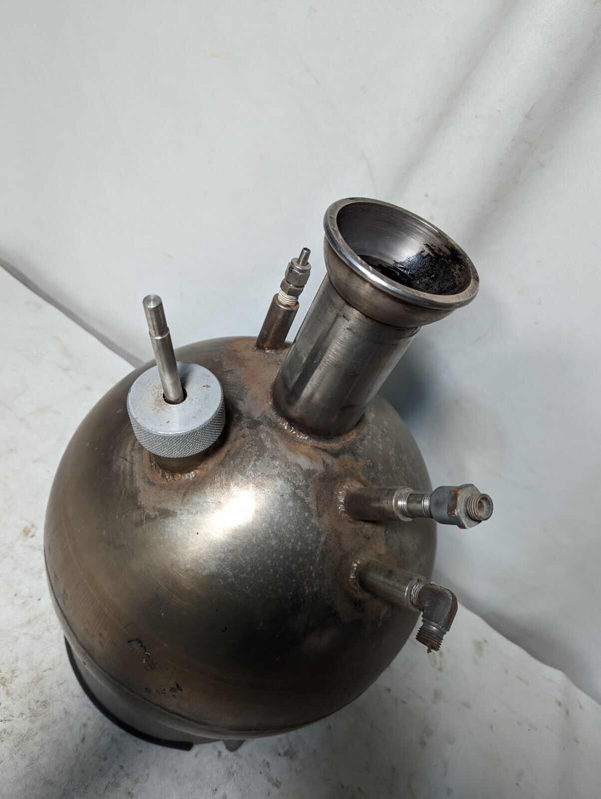Unbranded stainless steel spherical kettle with stand, has some asphalt inside