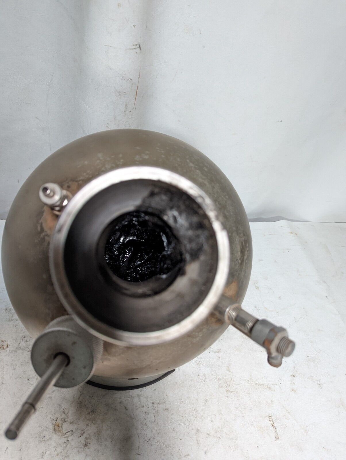 Unbranded stainless steel spherical kettle with stand, has some asphalt inside